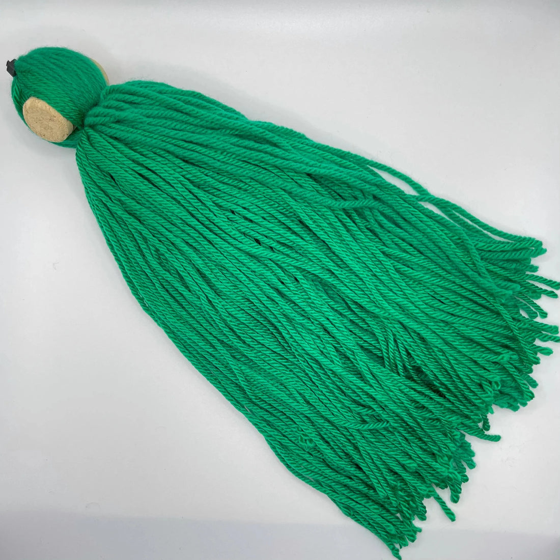 DIY spawning mop made of green acrylic yarn tied to a cork, floating in an aquarium for egg-laying fish