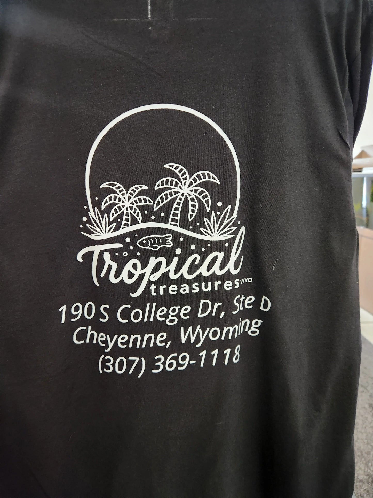 Black Tropical Treasures Wyo T-shirt with white palm tree logo and Cheyenne, Wyoming shop address printed on front
